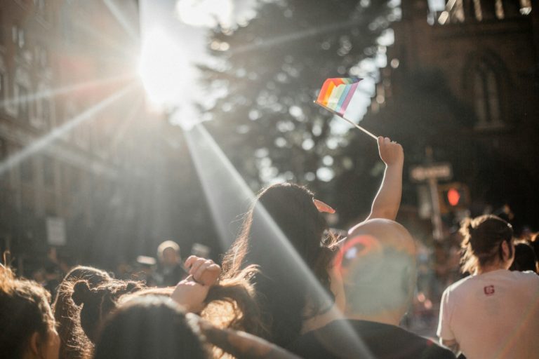 woman raising rainbow flag in crowd